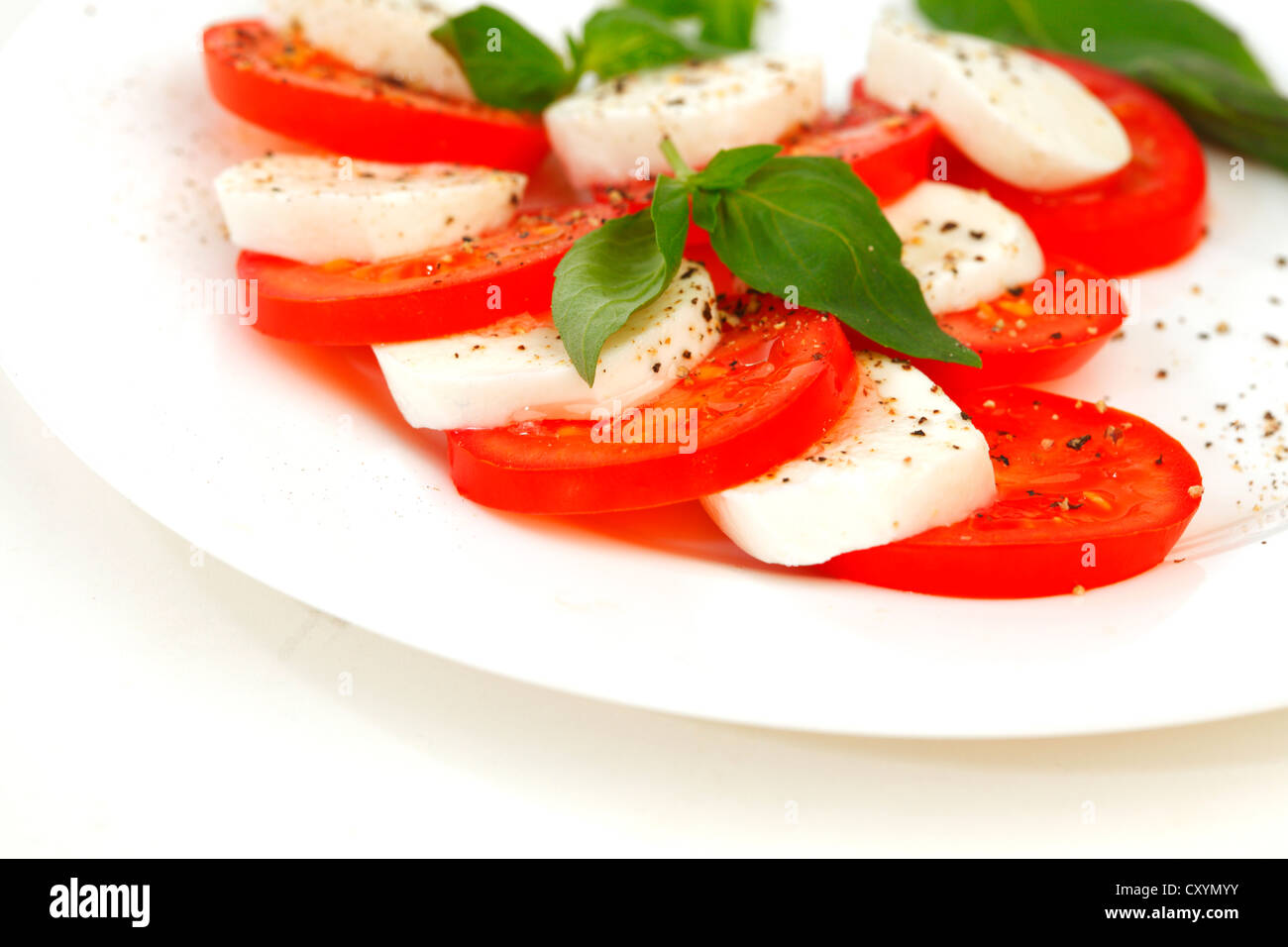 Tomate und Mozzarella mit Basilikum Blätter auf einem Teller Stockfoto
