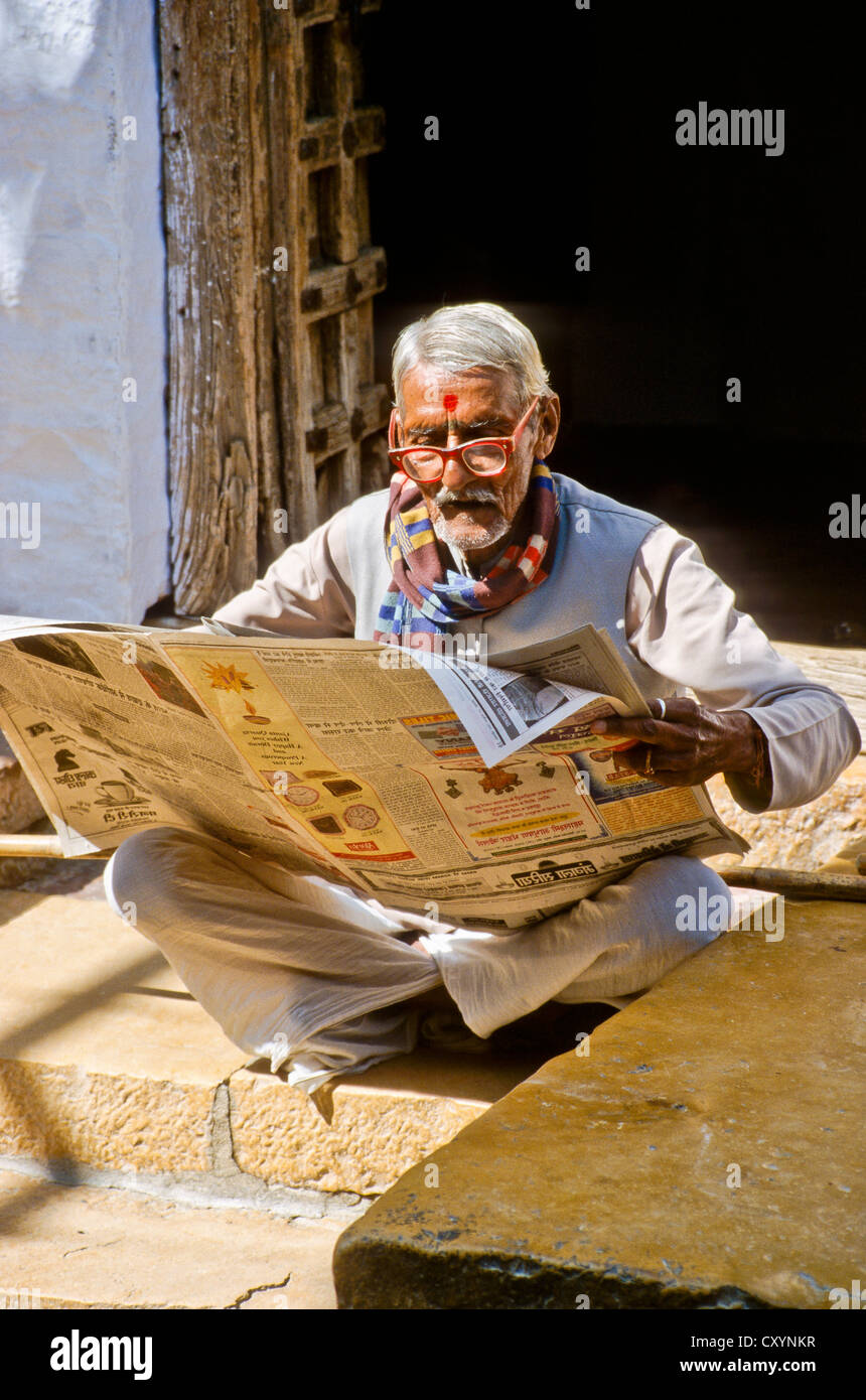 Alter Mann mit Brille lesen Zeitung in den Straßen von Jaisalmer, Indien, Asien Stockfoto