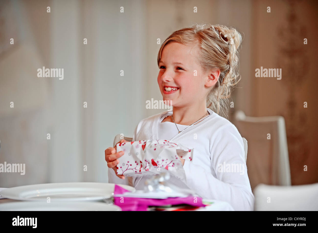 Mädchen, 9 Jahre, Auspacken Geschenk am Tag ihrer Erstkommunion, Region Münsterland, Nordrhein-Westfalen Stockfoto