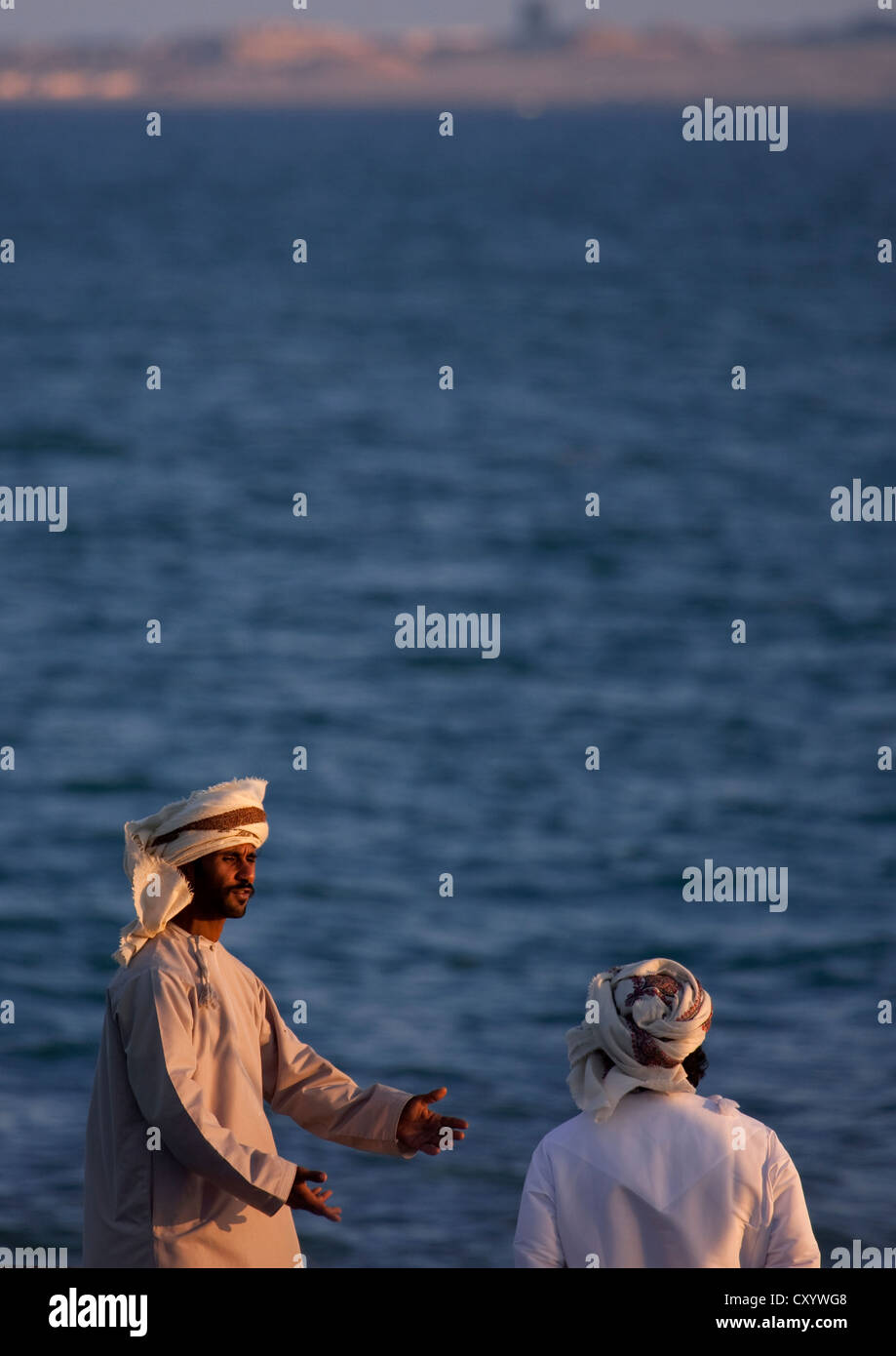 Zwei Männer im Chat mit dem Hintergrund des Meeres, Masirah Island, Vereinigte Arabische Emirate Stockfoto