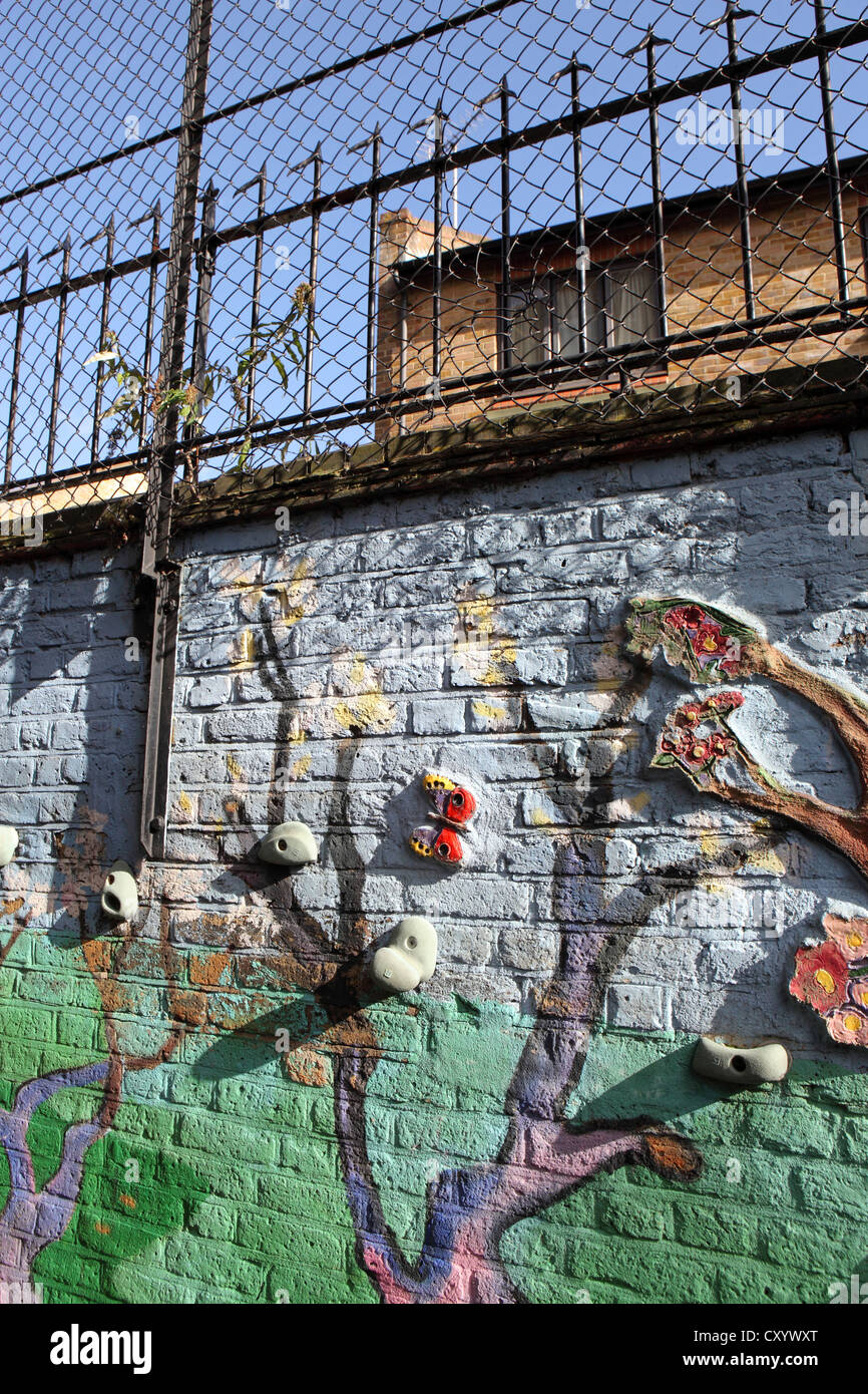 Gestaltete Spielplatz Wand London Grundschule, vertikales Bild mit Sicherheitszaun und Gebäude hinter London, UK Stockfoto