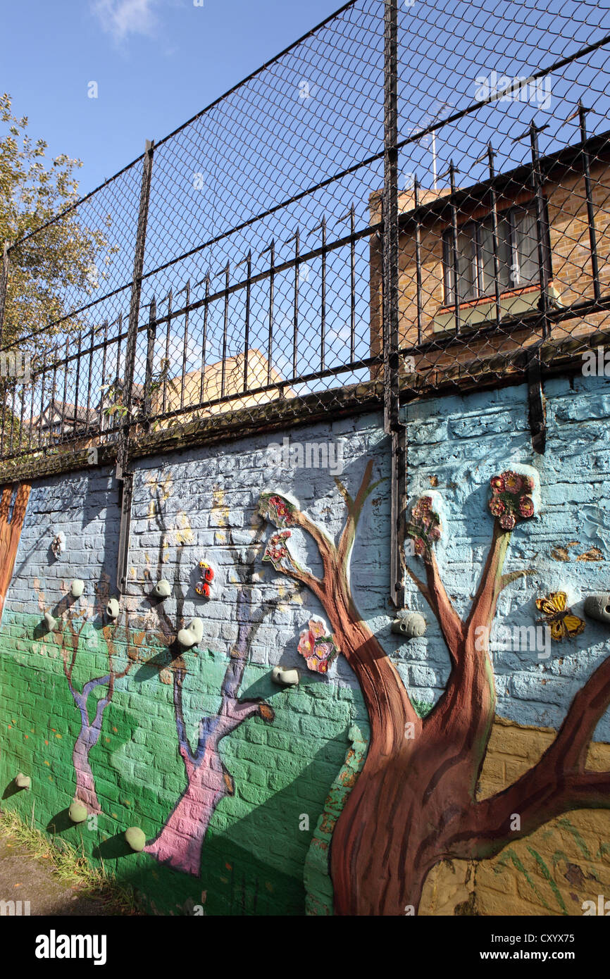 Gestaltete Spielplatz Wand London Grundschule, vertikales Bild mit Sicherheitszaun und Gebäude hinter London, UK Stockfoto