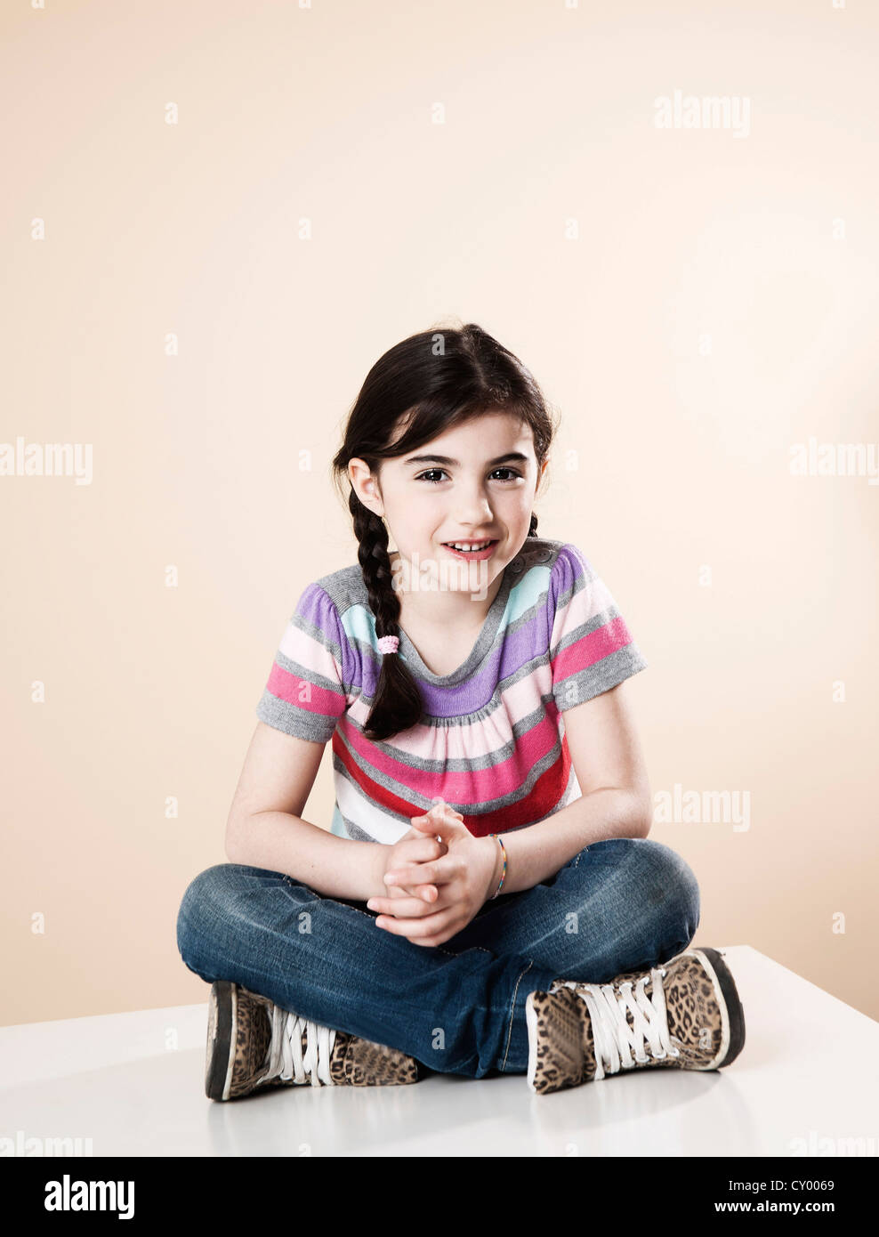 Lächelndes Mädchen sitzend mit Beine gekreuzt Stockfoto