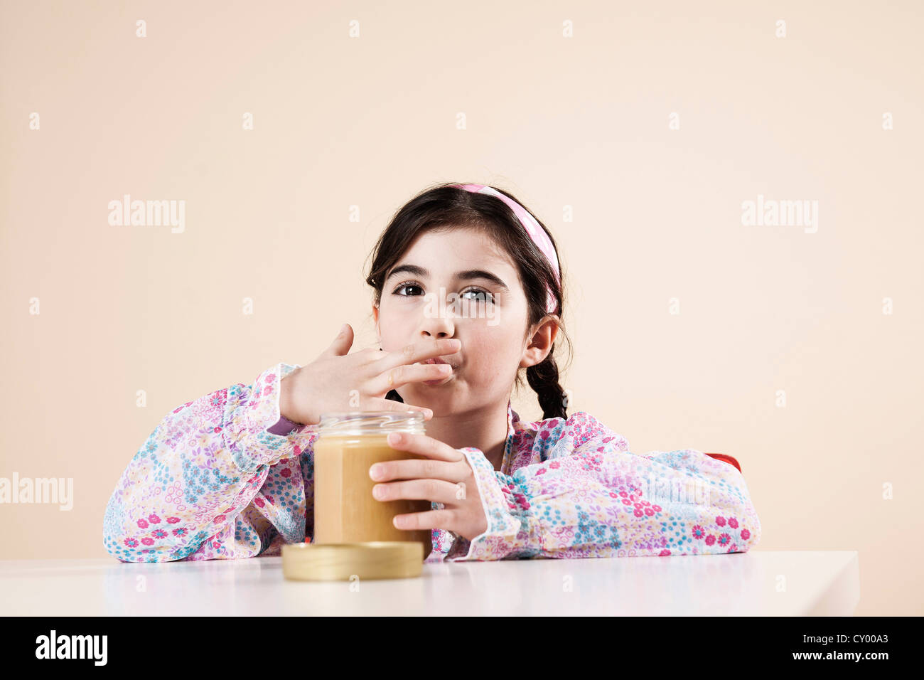 Mädchen, Nibbeln angenehm aus ein Glas Honig Stockfoto