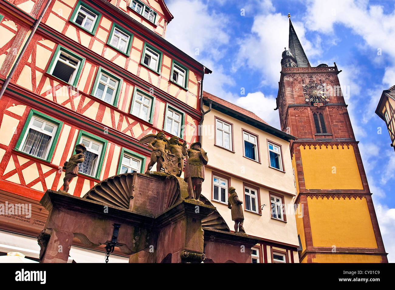 Wertheim, Franken, Deutschland, eine mittelalterliche Wasser gut vor Kreuz Fachwerkhäuser und ein Clock tower Stockfoto
