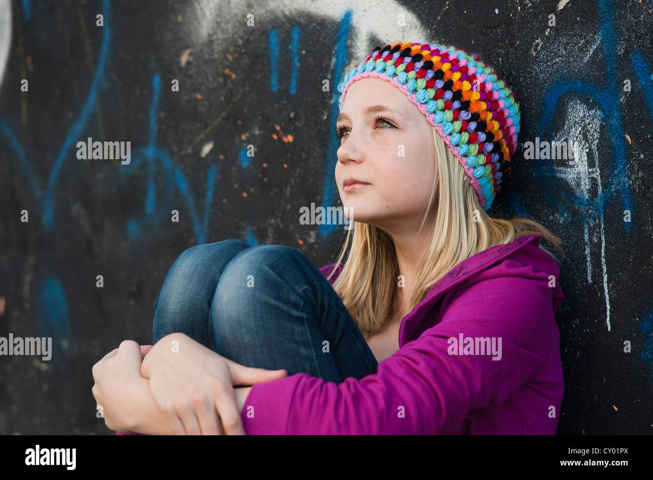 Mädchen tragen eine Strickmütze sitzen vor einer Wand mit graffiti Stockfoto