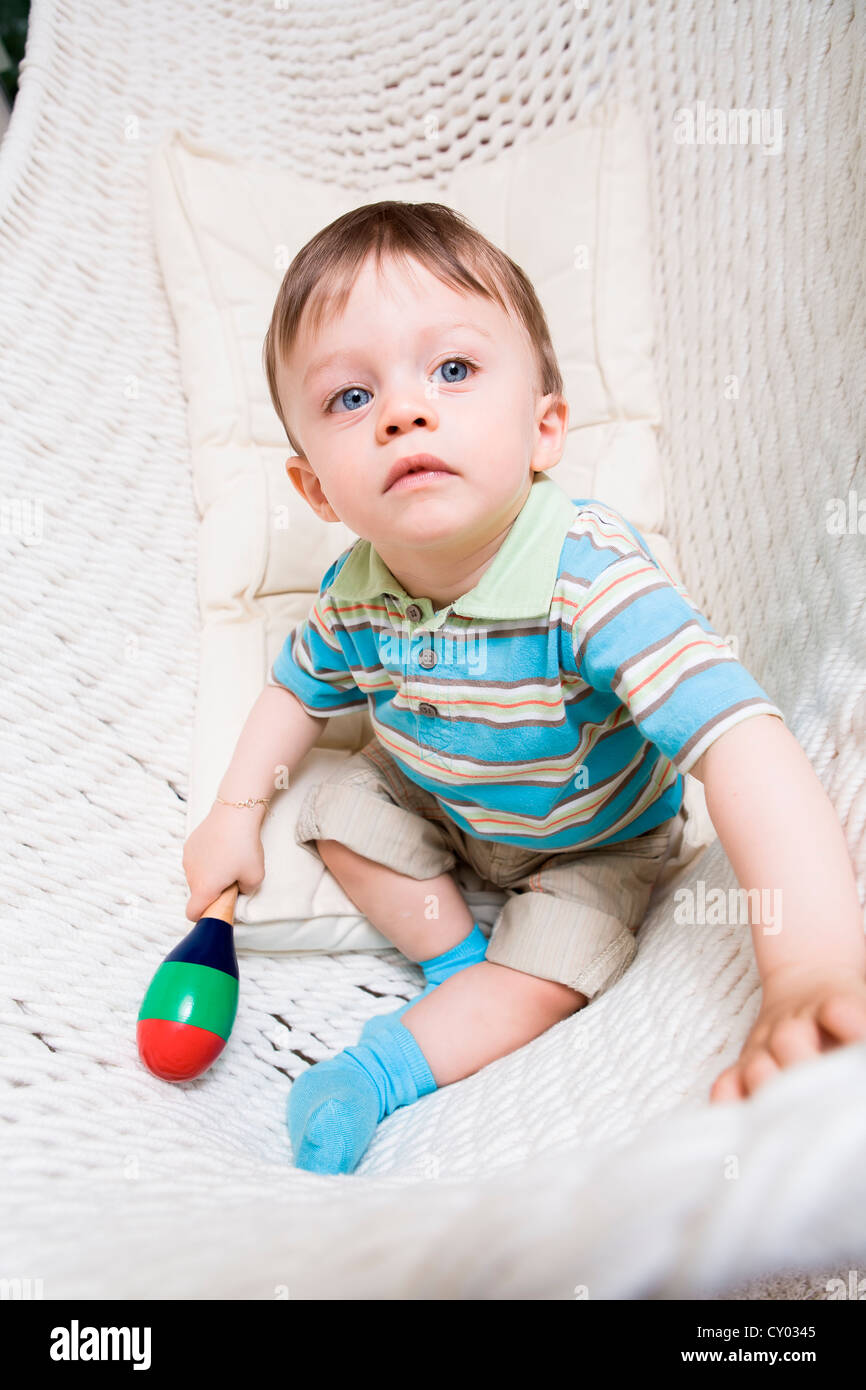 Junge, 1 Jahr, mit Rassel, sitzen in einer Hängematte Stockfoto