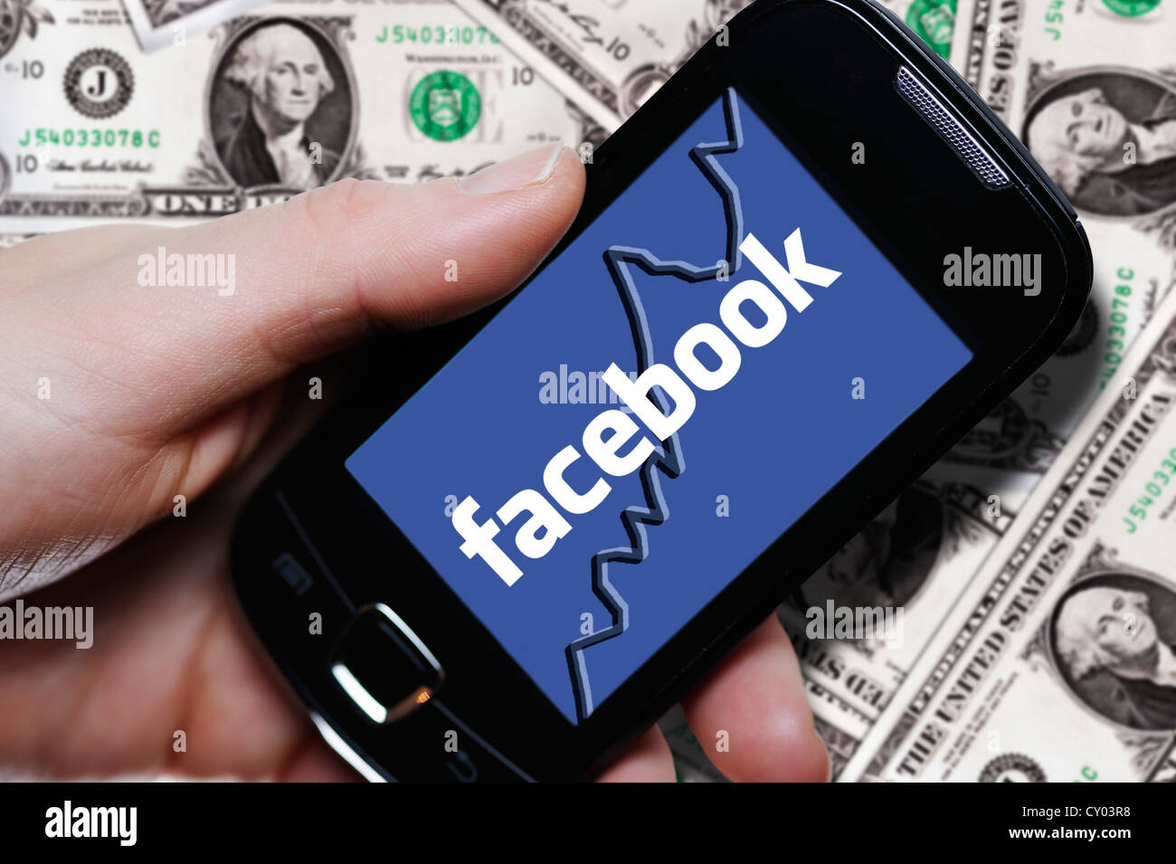 Hand, die eine Smartphone mit einem Facebook-Logo vor Dollarnoten, symbolisches Bild für Facebook IPO Stockfoto