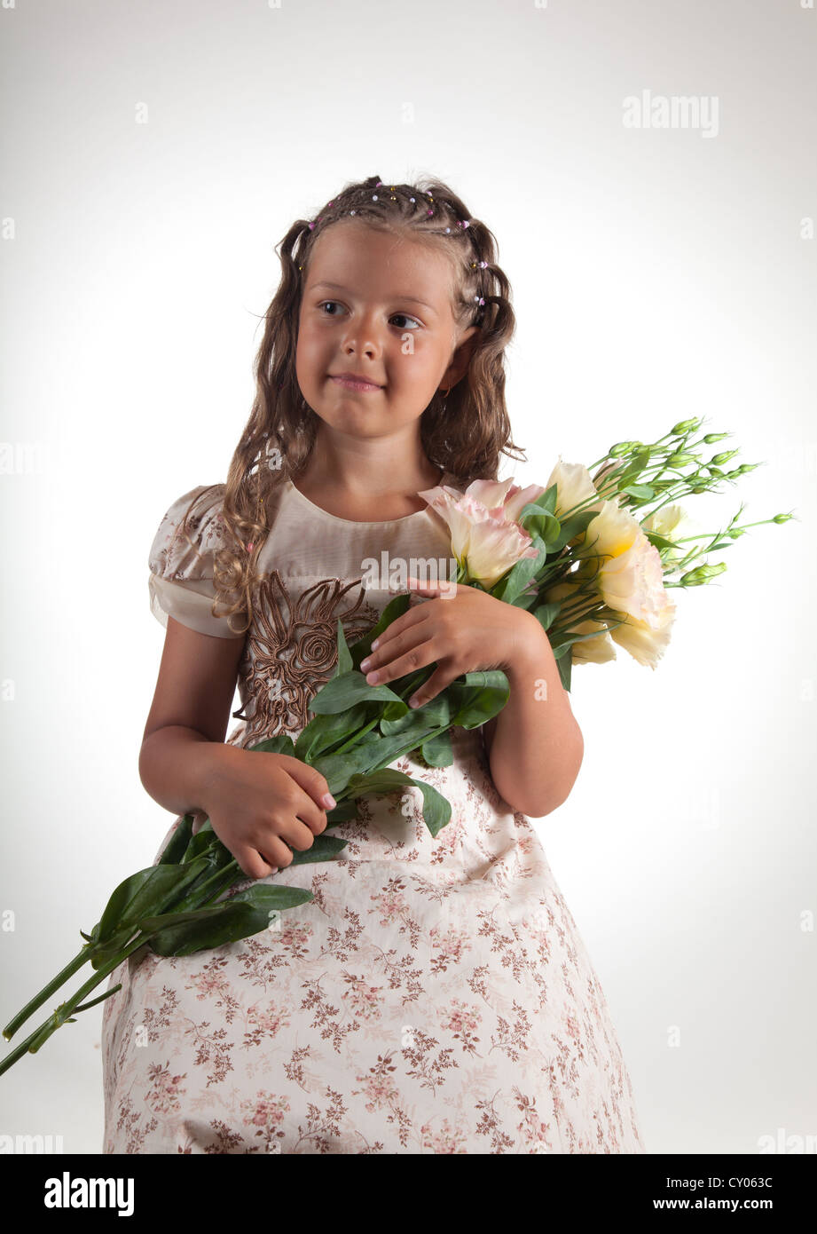 Niedliche kleine Mädchen mit Zopf Frisur hält Blumen, Studio gedreht Stockfoto