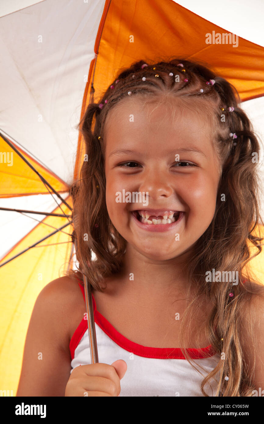 Kleines Mädchen hält Regenschirm und zeigt zwei fehlende Zähne Stockfoto