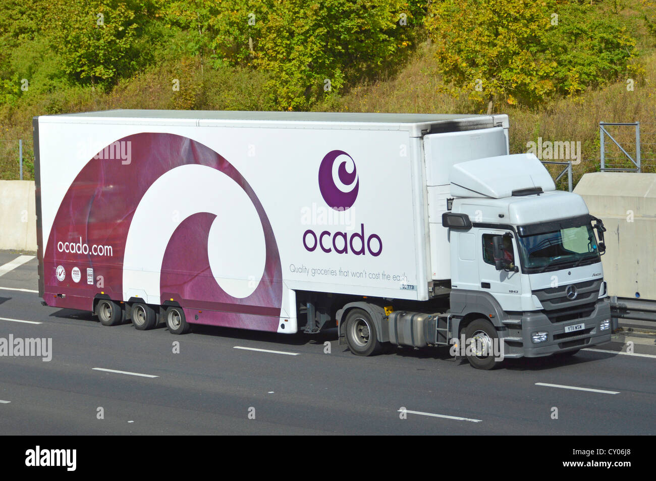 Ocado, seitlich gesehen, weißer Lebensmittelanhänger mit lilafarbener Grafik und seitlicher Vorderseite des mercedes Lieferwagens, der auf der englischen britischen Autobahn fährt Stockfoto