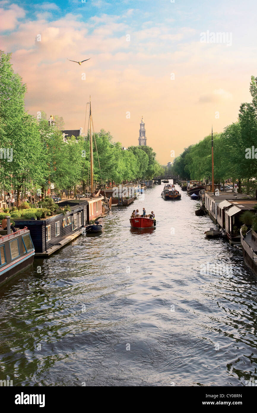Niederlande, Amsterdam, Boote fahren Sie entlang eines Kanals mit der Zuiderkerk Glockenturm im Hintergrund. Holland. Stockfoto