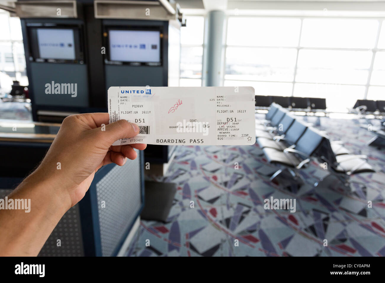 Hand hält eine Bordkarte. Flughafen-Gate im Hintergrund. Stockfoto