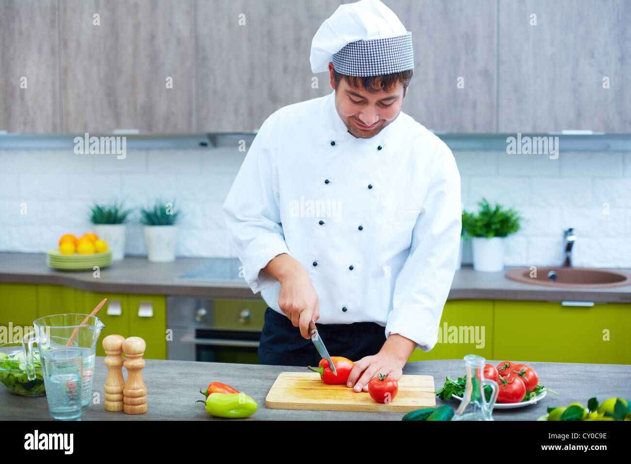 Bild des männlichen Chef mit Messer schneiden vegs auf Holzbrett Stockfoto