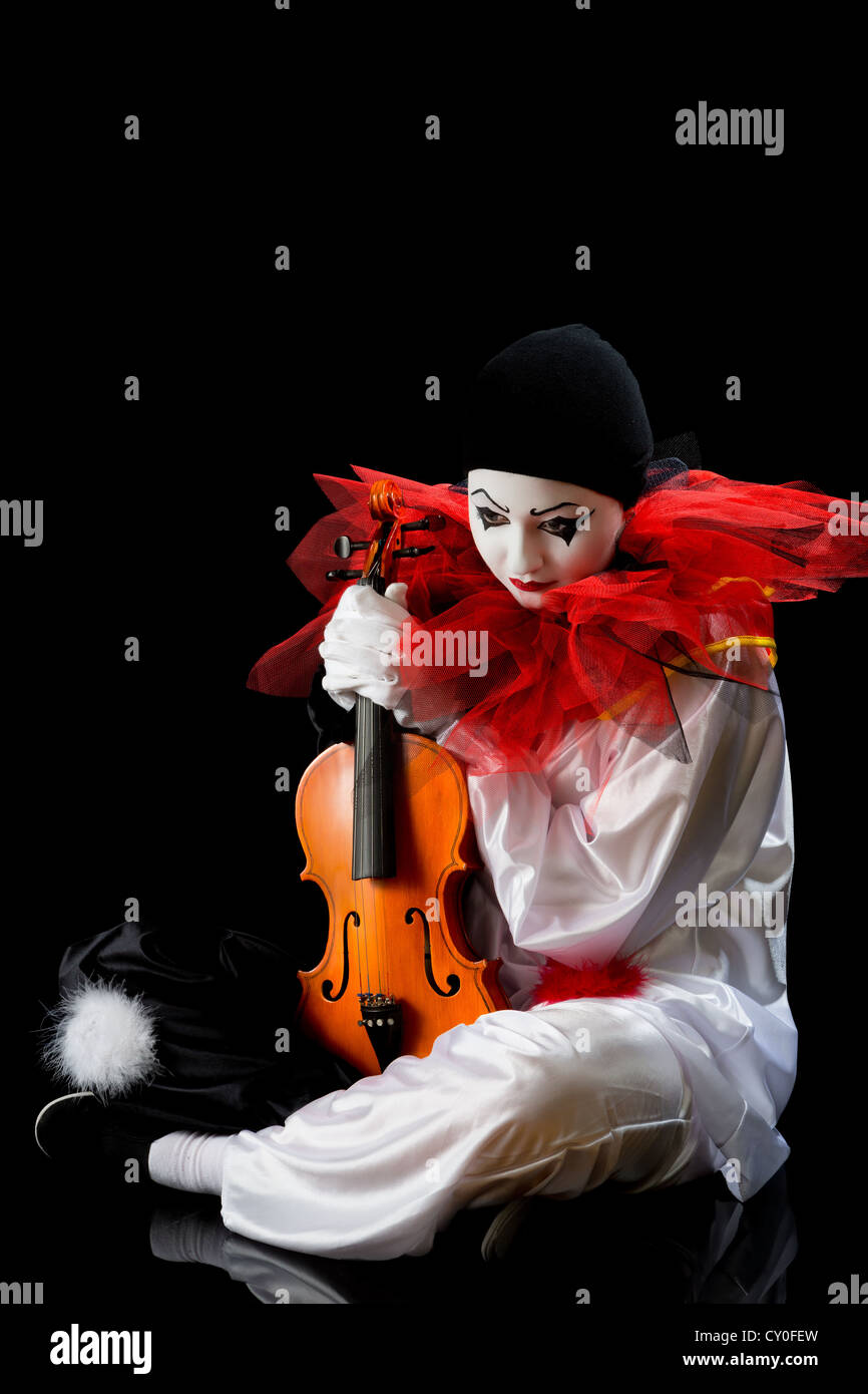 Traurigen Pierrot auf das Floow sitzend mit einer alten Geige Stockfoto