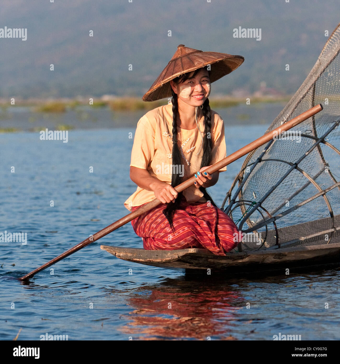 Myanmar, Burma. Junge burmesische Frau mit ihrem Kanu und Netzstrümpfe. Inle-See, Shan-Staat. Stockfoto