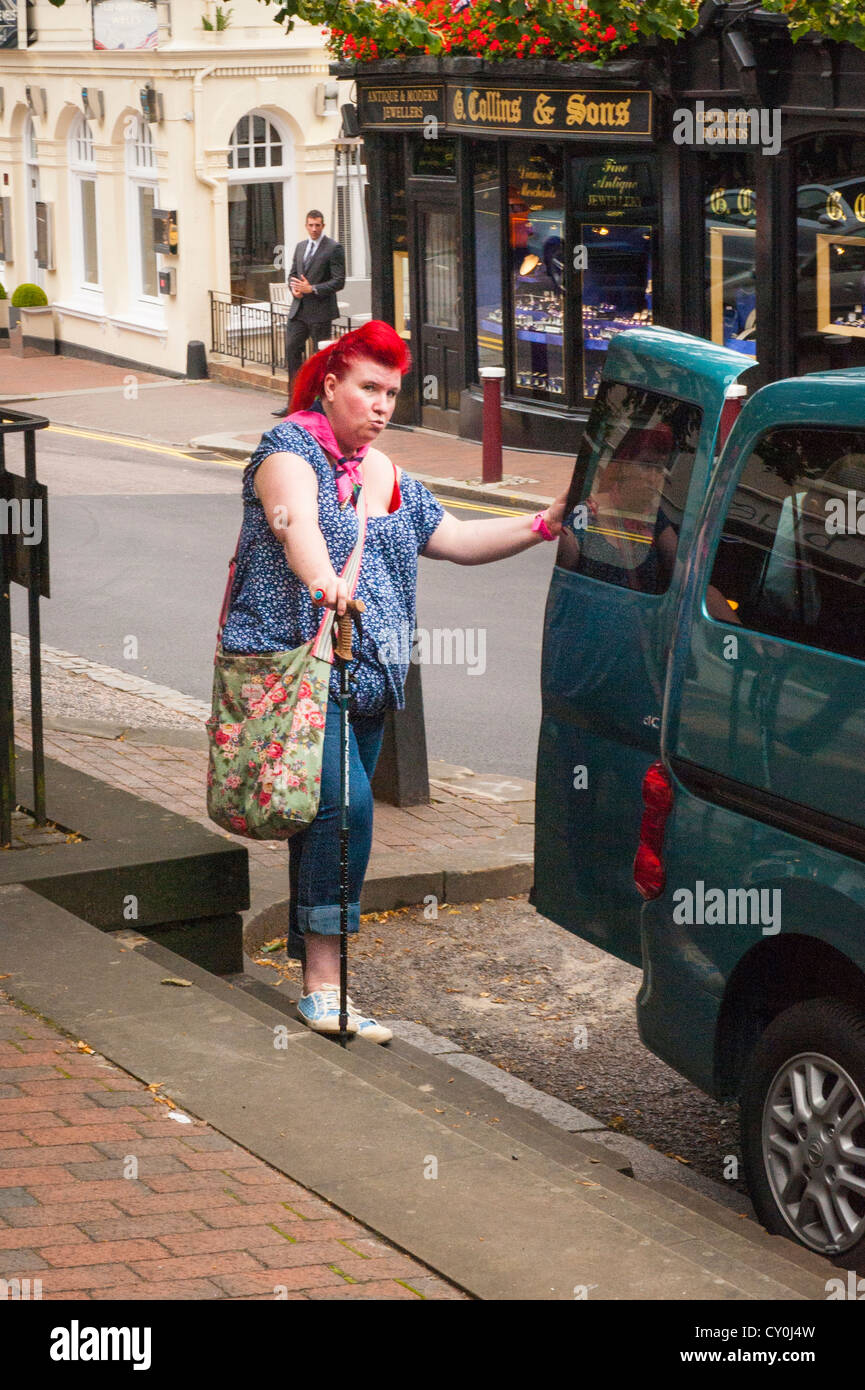 Kent Royal Tunbridge Wells High Street bunte deaktiviert grosse Frau Frau Frau mit roten Haaren & Walking Stick geladen Auto street scene Stockfoto
