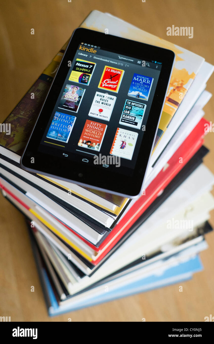 Google Nexus 7 Tablet-Computer mit kindle e-Book-Bibliothek-Anwendung und Haufen von traditionellen Hardcover Bücher Stockfoto