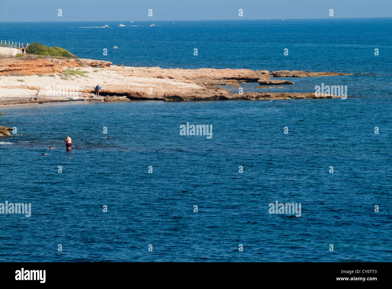 Personen, die ein Bad an einem felsigen Strand, Les Rotes Denia, Kap San Antonio, Provinz Alicante, Spanien, Europa Stockfoto