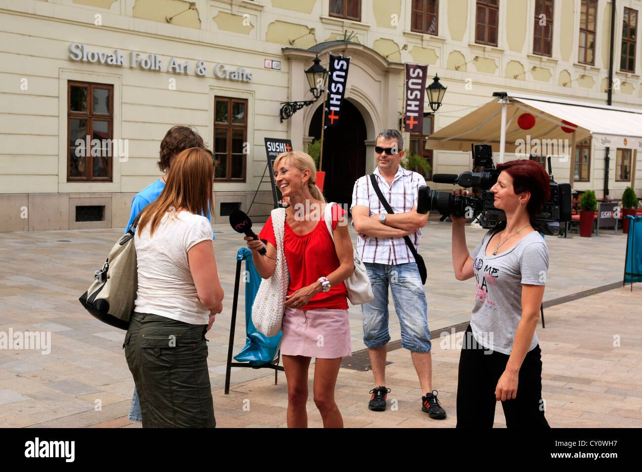 Weiblichen TV-Reporter und Film crew interviewen Passanten in Bratislava Altstadt während ein folk-Festival-Wochenende Stockfoto