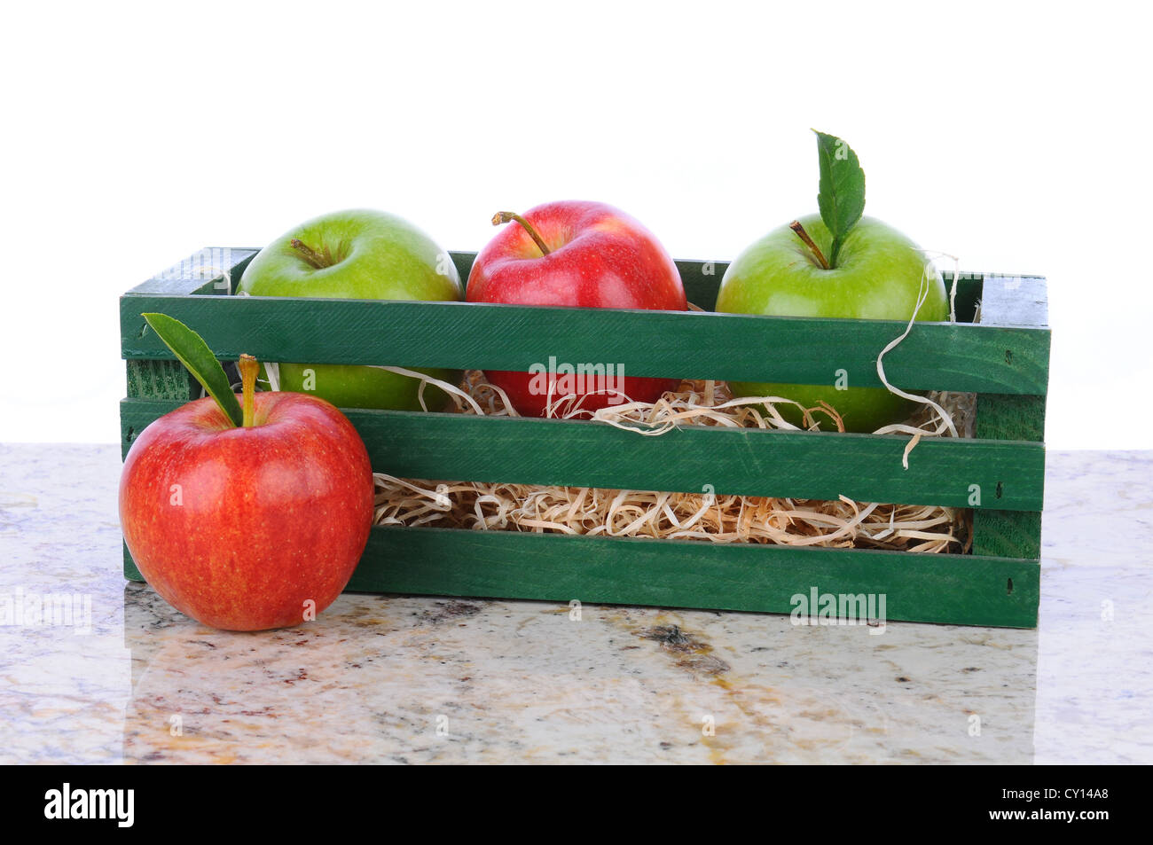 Granny Smith oder Gala Äpfel in einer Holzkiste auf eine Granit-Arbeitsplatte. Querformat mit einem weißen Hintergrund. Stockfoto