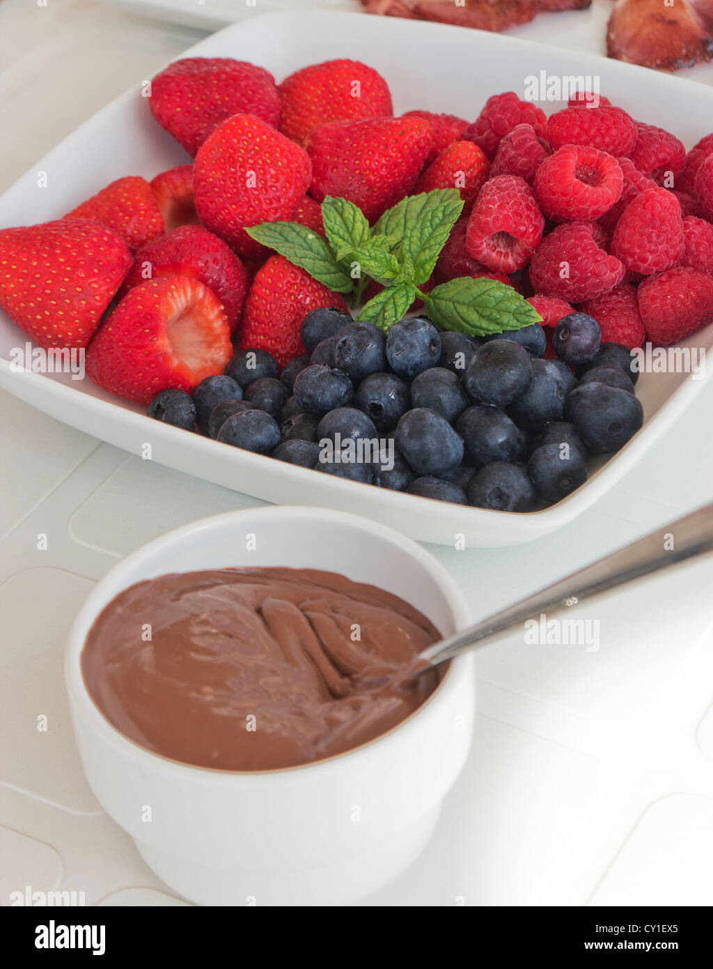 Teller mit gemischten Früchten und kleine Schüssel Schokoladen Dip. Stockfoto