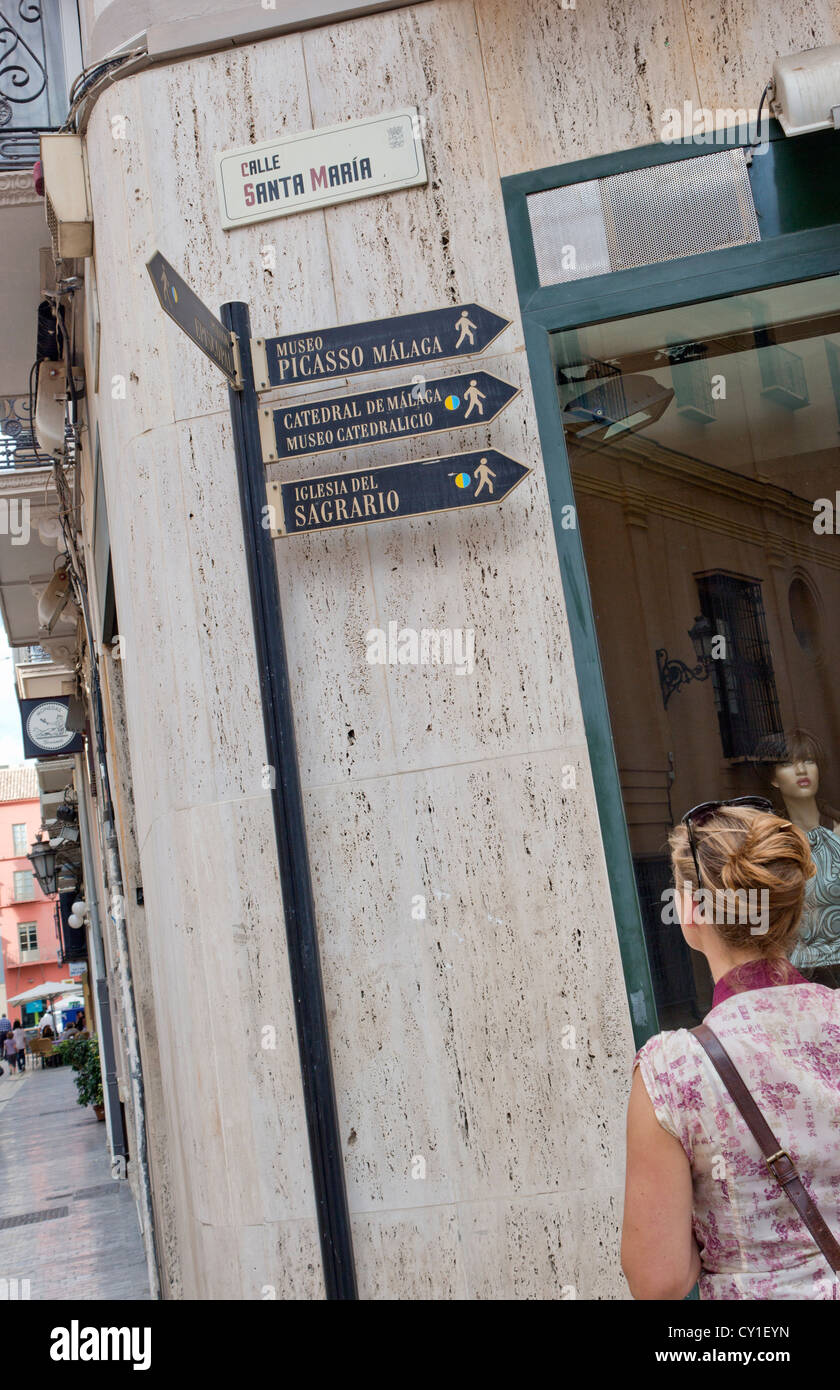 Málaga, Costa Del Sol, Andalusien, Spanien. Junge Frau Zeichen mit Wegbeschreibungen zu den Sehenswürdigkeiten betrachten. Stockfoto
