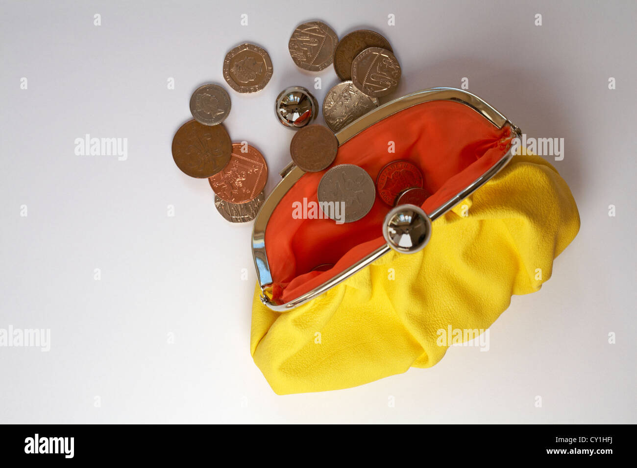 Kleingeld fallen aus gelben Geldbörse mit Orange farbigen innen isoliert auf weißem Hintergrund Stockfoto