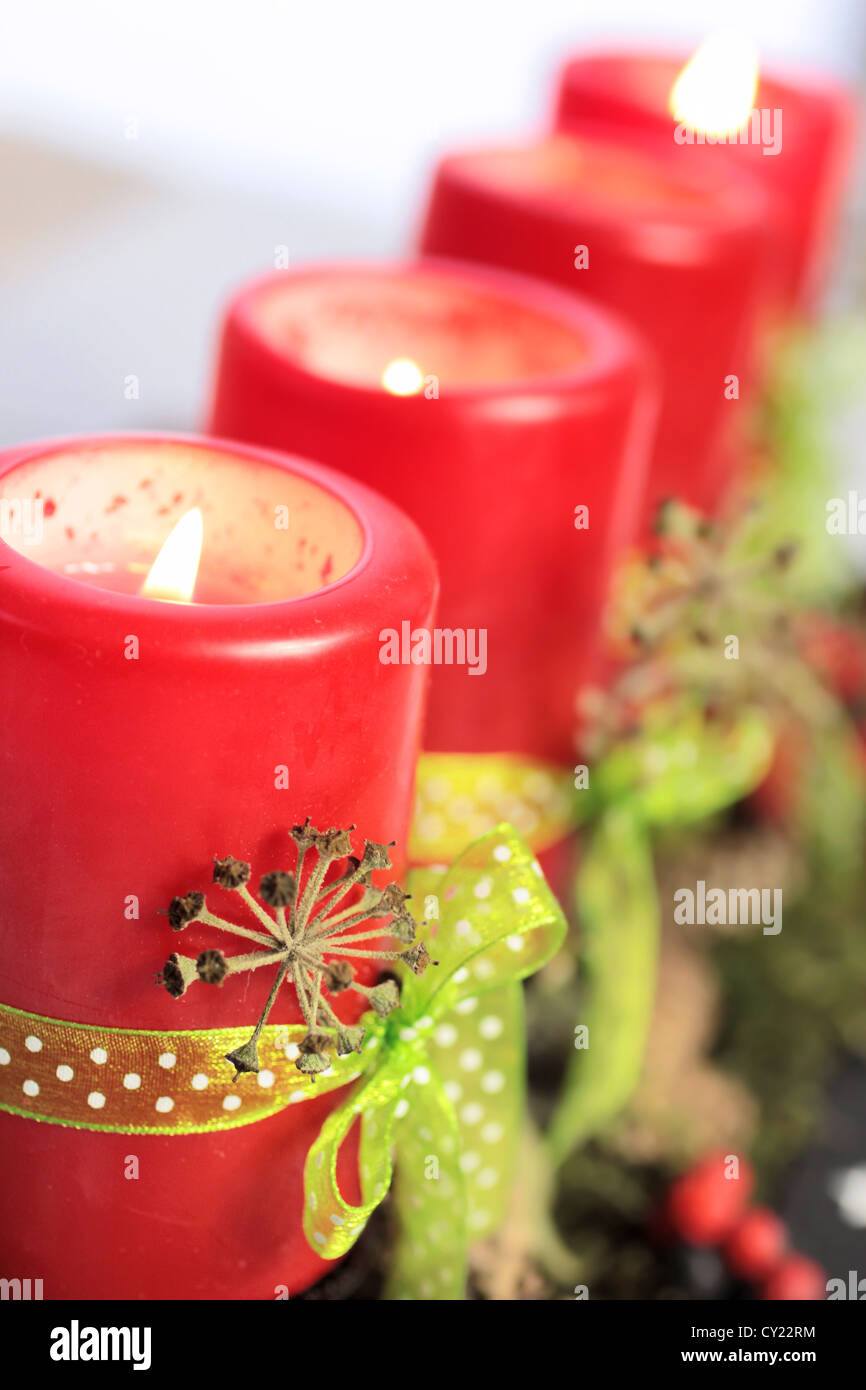 Vier brennende rote Advent Kerzen mit grünen Bändern Stockfoto