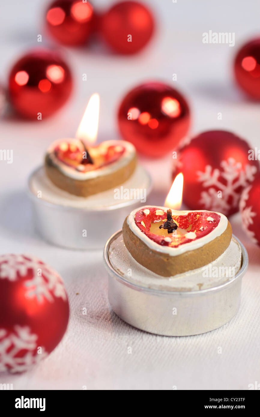 Brennende Kerzen in Herzform mit Weihnachtskugeln und Herzen Stockfoto