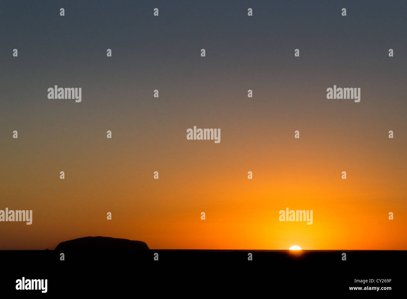 Schwarze Silhouette des Uluru in der aufgehenden Sonne. Stockfoto