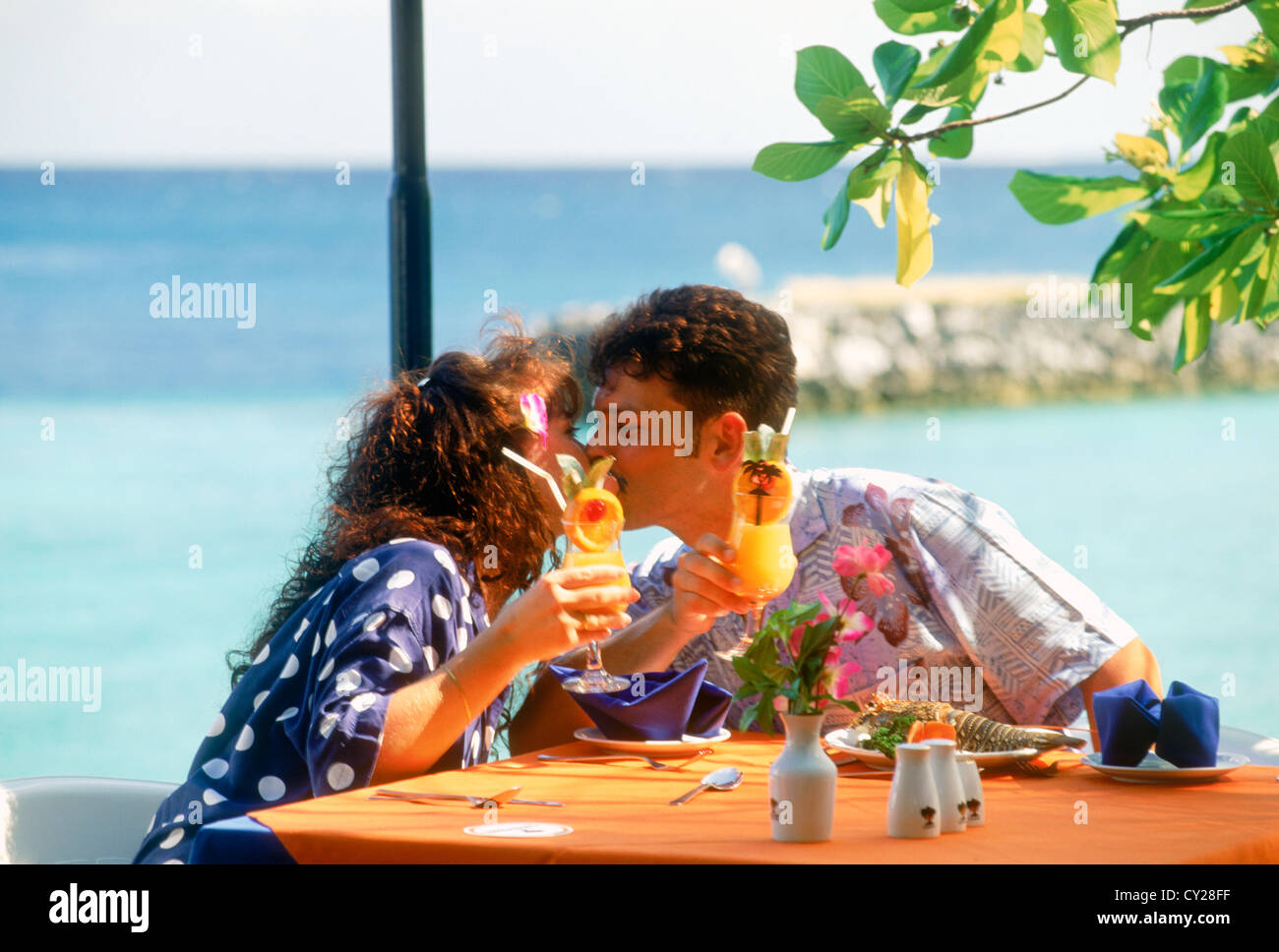 Paar küssen und halten tropische Drinks im Außenrestaurant auf Fihalhohi Insel in der Inselgruppe im Indischen Ozean Stockfoto
