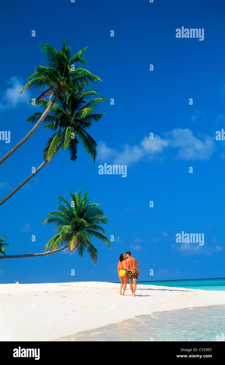 Paar zu Fuß und küssen unter Palmen am weißen Sandstrand tropischen Insel Strand auf den Malediven Stockfoto