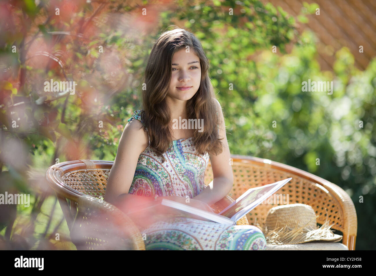 Mädchen lesen Buch im Korbstuhl in Sommertag im Freien sitzen Stockfoto