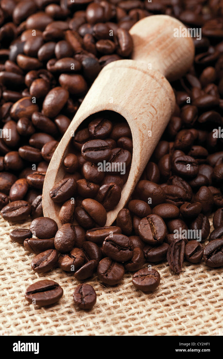 Nahaufnahme von Kaffeebohnen mit Holzlöffel auf Leinen material Stockfoto