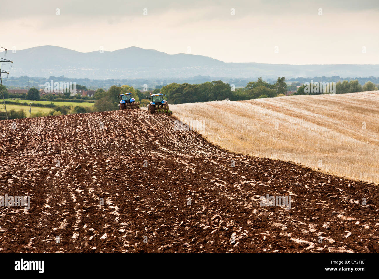 zwei Traktoren pflügen ein Feld in der Nähe von Malvern Hills Worcestershire.landscape Bild. Stockfoto