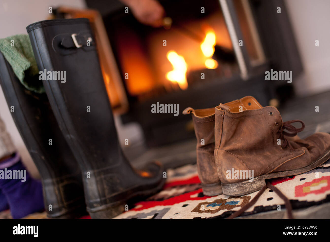 Stiefel und Gummistiefel vor dem offenen Kamin in einem Ferienhaus in Cornwall im winter Stockfoto