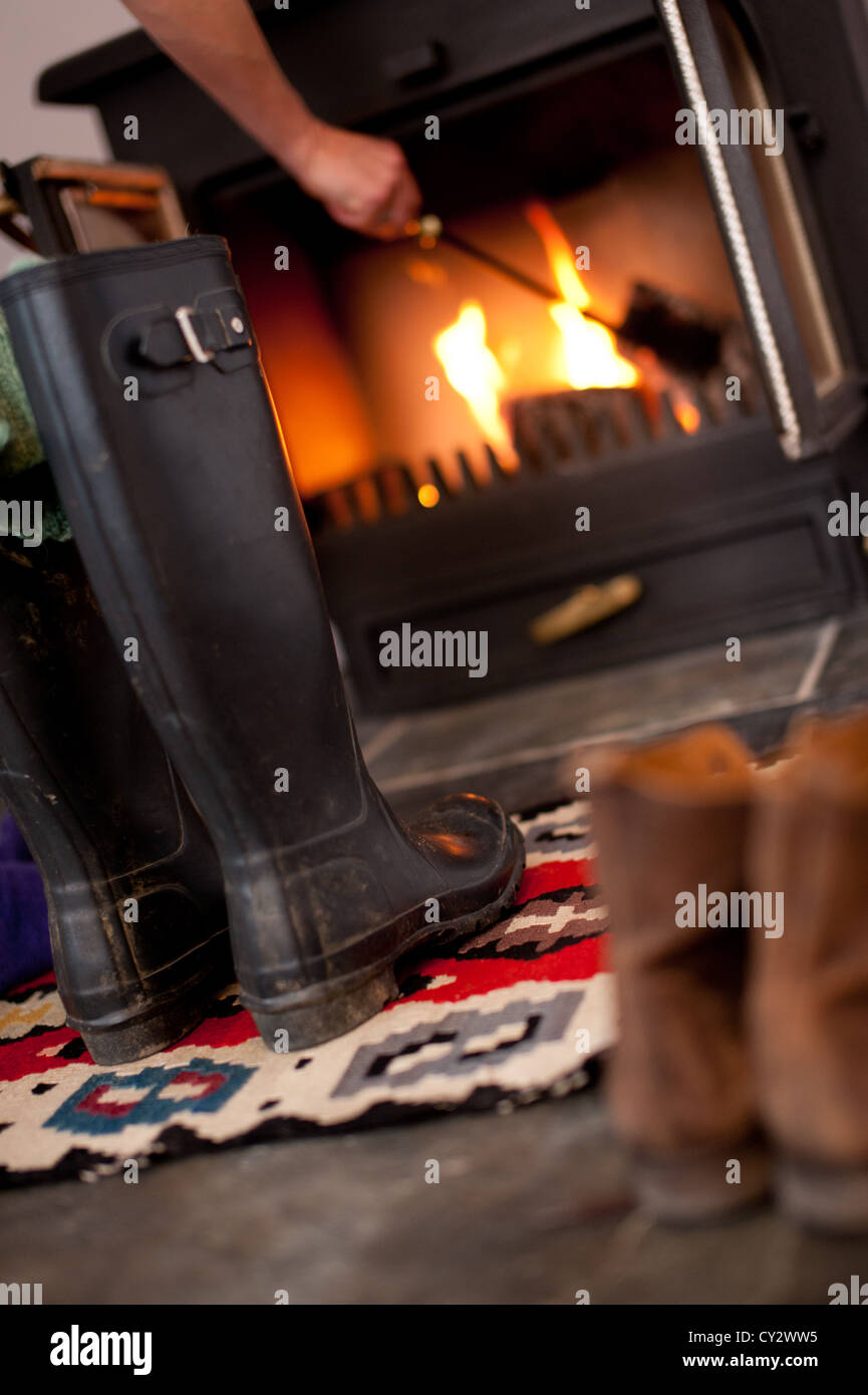 Stiefel und Gummistiefel vor dem offenen Kamin in einem Ferienhaus in Cornwall im winter Stockfoto