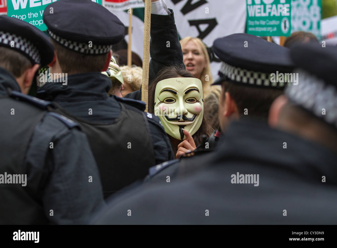 Ein maskierter Guy Fawkes Demonstrant am stoppen der Krieg Kundgebung in Trafalgar Sq, London sieht durch die Polizeilinien. Stockfoto