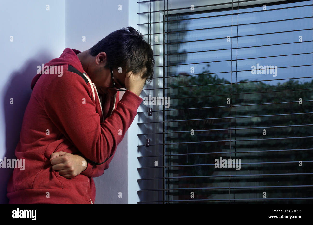 Junger Mann von einem Fenster Hand auf Kopf stehen. Stockfoto