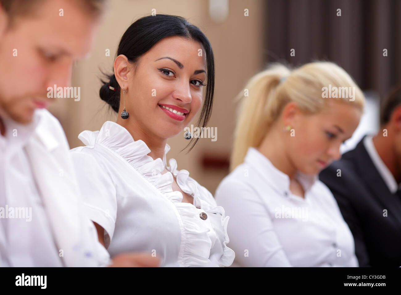 Lächelnde Frau sitzt an einem Business-Meeting mit Kollegen im Büro Stockfoto