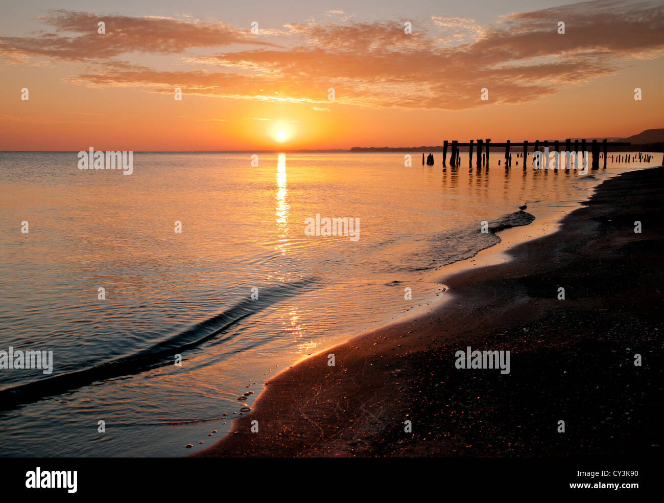 Sonnenaufgang über eine noch Lake Ontario, mit alten Pfeilern und Böschung im Hintergrund Stockfoto