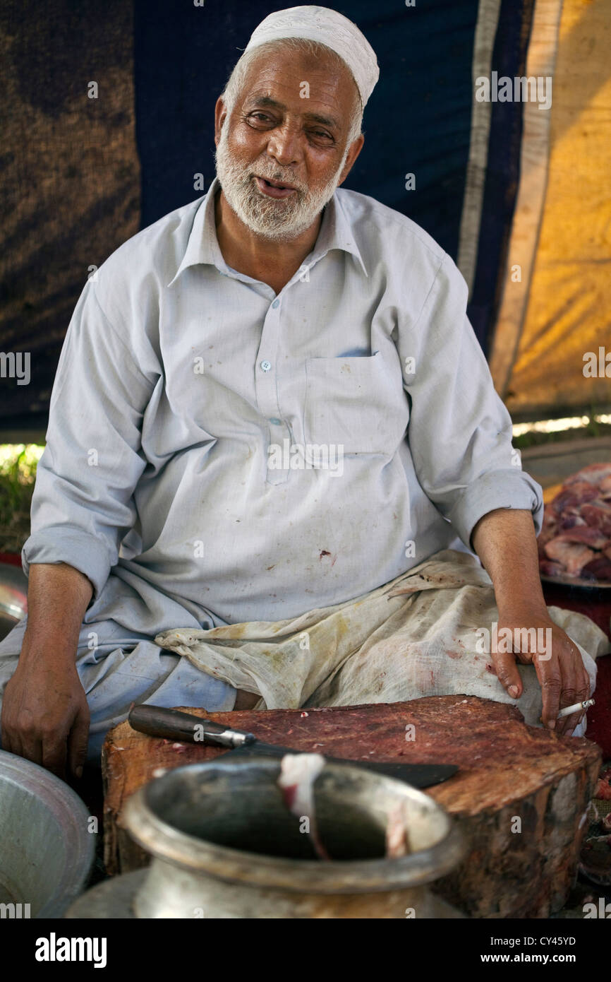 Gulam Ahmed, 60, eine Waza oder Kochen in der Wazwan Tradition raucht eine Zigarette, wie er Fleisch in Vorbereitung auf eine Wazwan fest hackt. Stockfoto