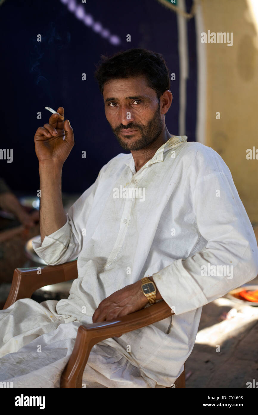 Eine Wazas oder Kochen in der Wazwan Tradition raucht eine Zigarette vor einer Wazwan fest. Srinagar, Kaschmir, Indien Stockfoto