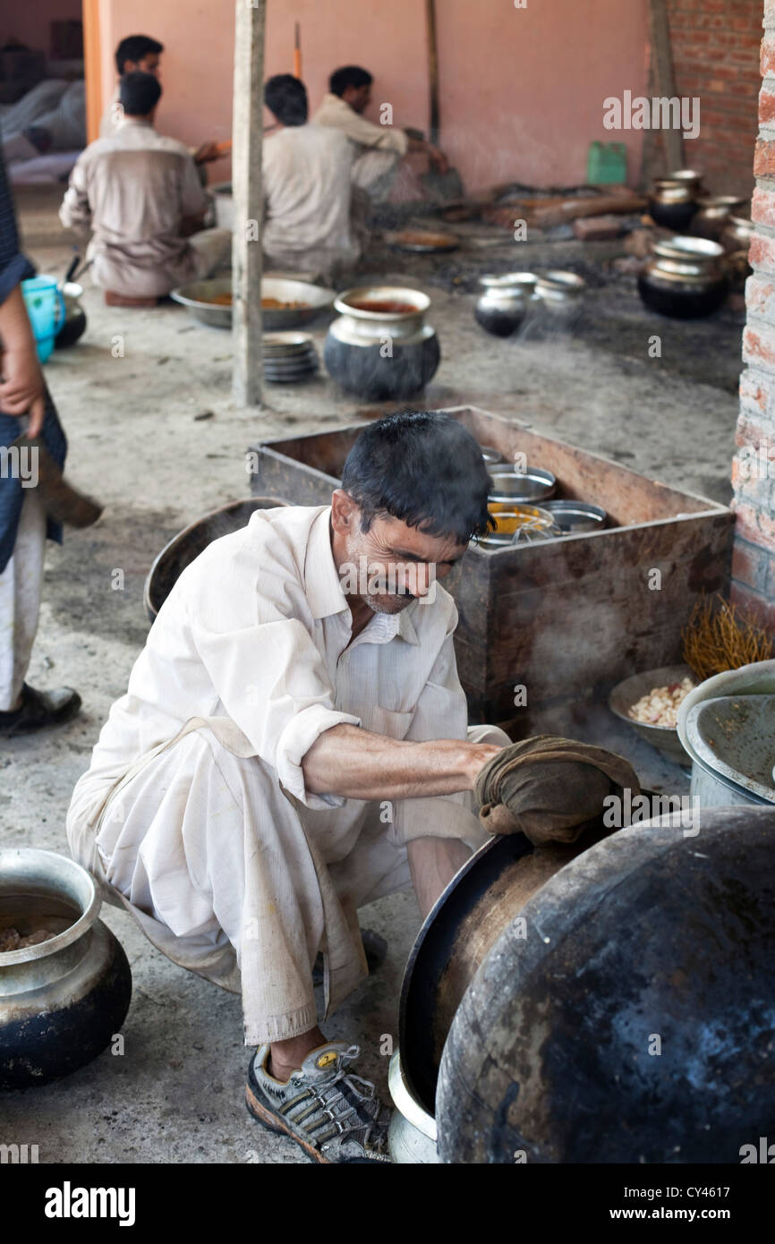 Ein Waza oder Köche in der Wazwan Tradition mündet einen Topf mit Essen in Vorbereitung auf eine Wazwan fest. Srinagar, Kaschmir, Indien Stockfoto