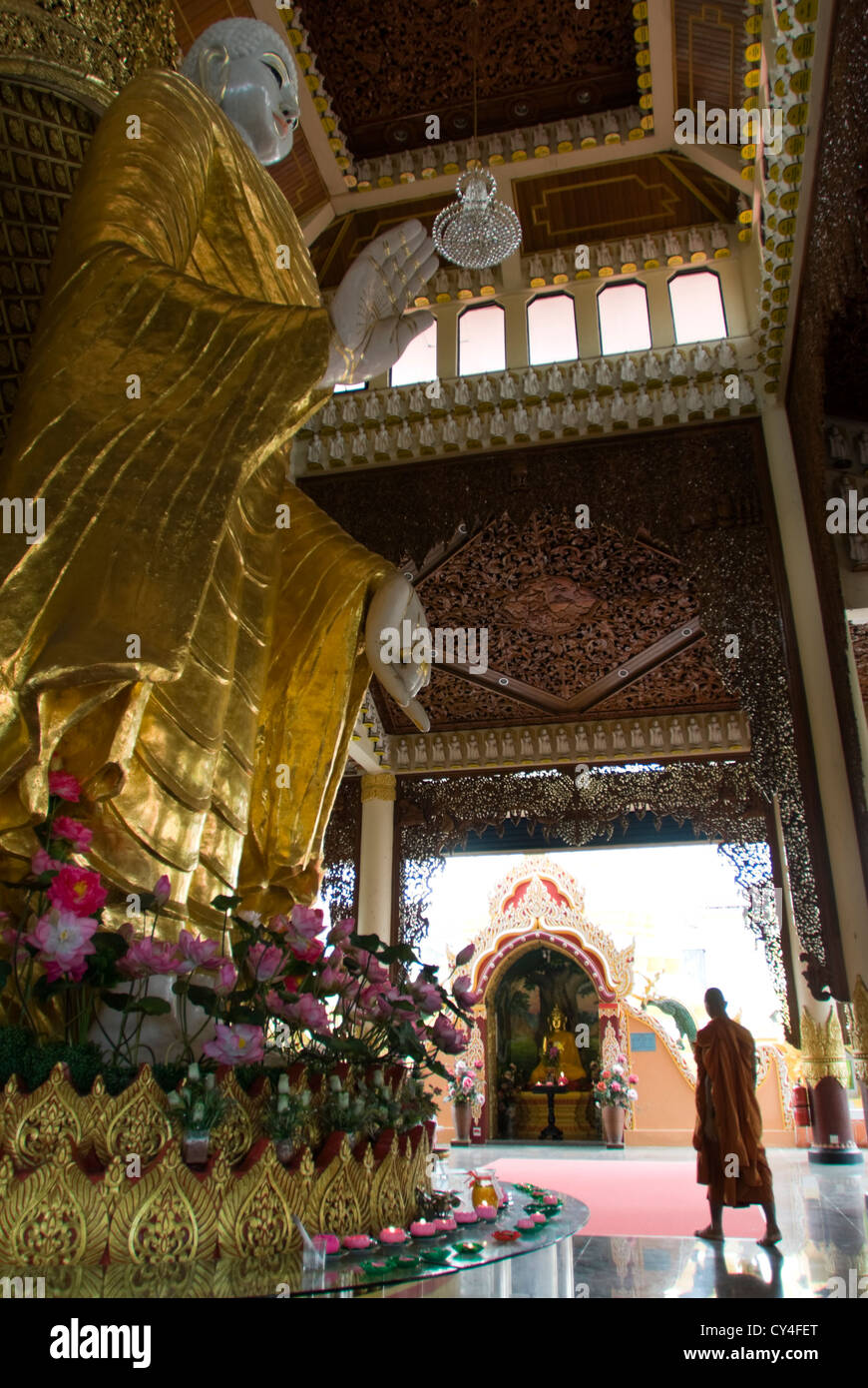 Ein Mönch führt durch eine Halle mit einer großen Statue des Buddha. Dhammikarama Burmesen buddhistische Tempel, Penang, Malaysia. Stockfoto