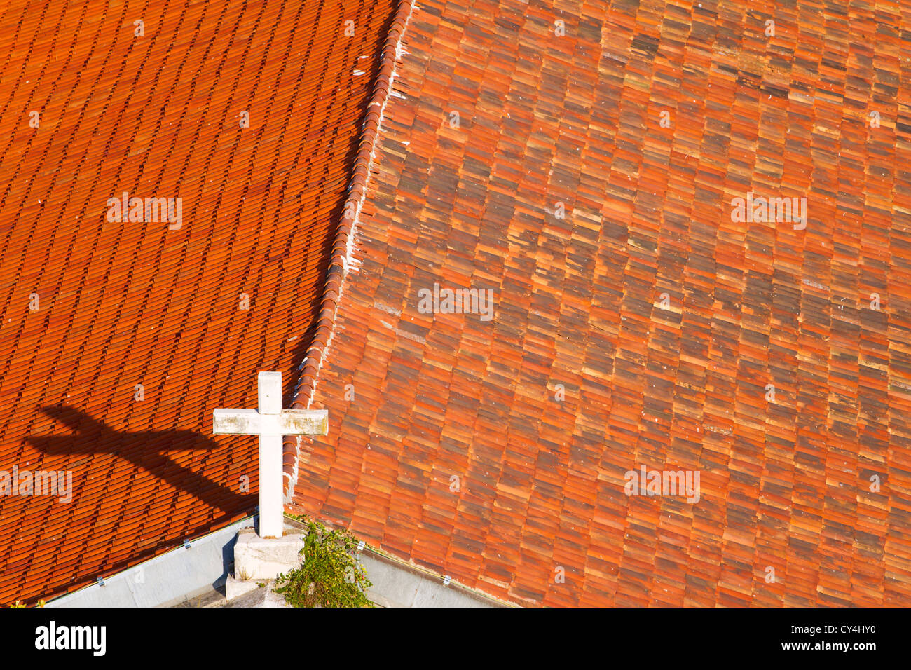 Kreuz auf der Kirche auf dem Dach mit orange Fliesen bedeckt Stockfoto