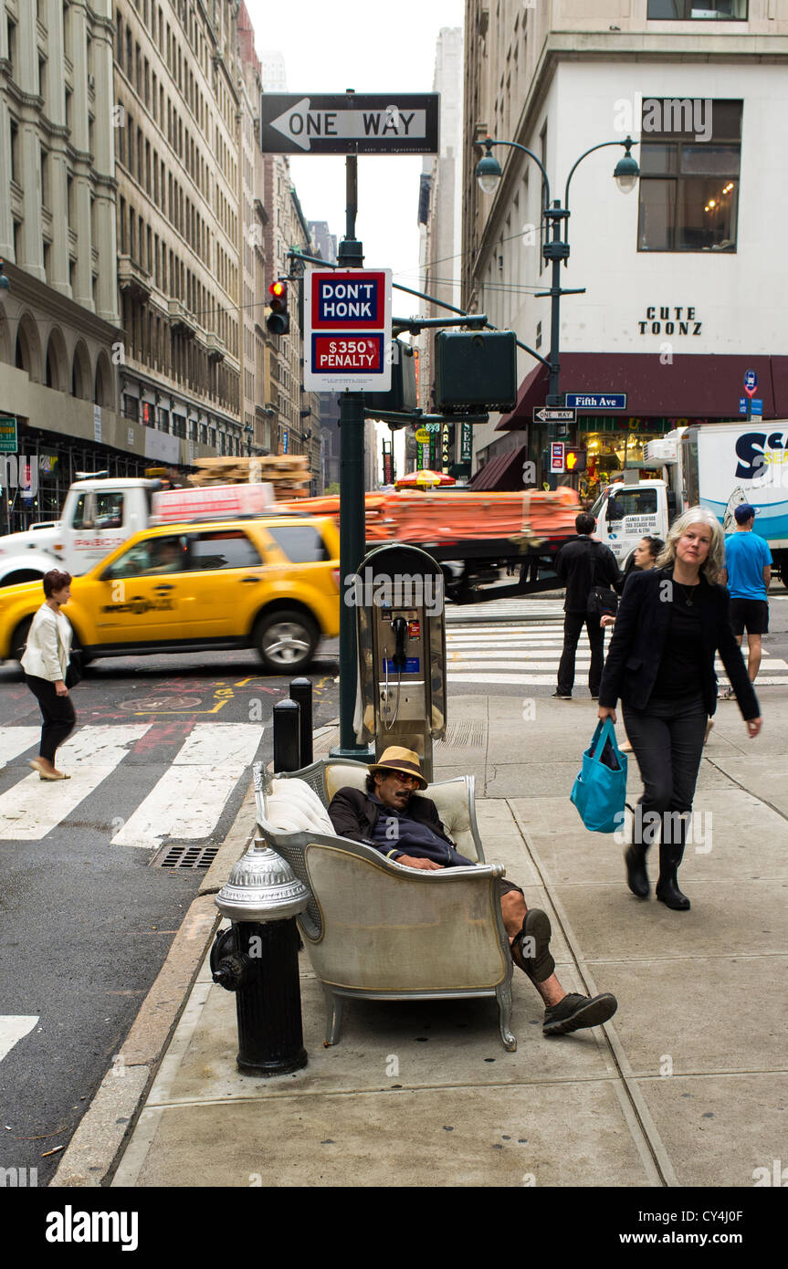 Ein Mann schläft auf der Couch auf einem geschäftigen Manhattan Bürgersteig. Stockfoto