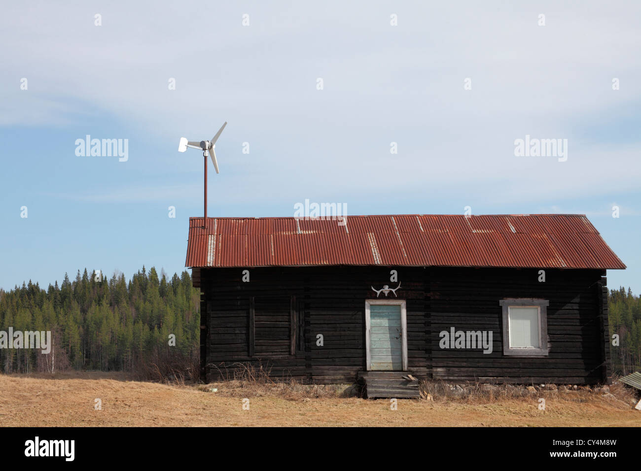 Blockhaus mit kleine Windkraftanlage auf das Metalldach verkleidet Stockfoto