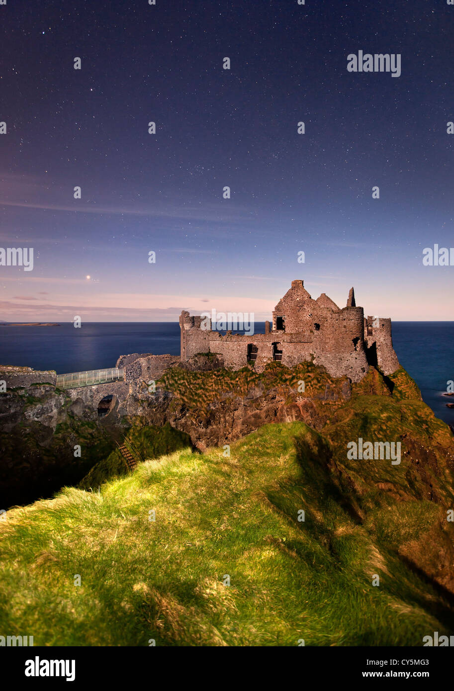 Dunluce Castle gefangen in der Nacht im Mondlicht. Stockfoto